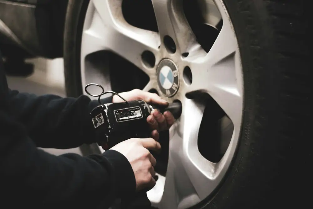 Mechanic using an impact wrench on a car wheel